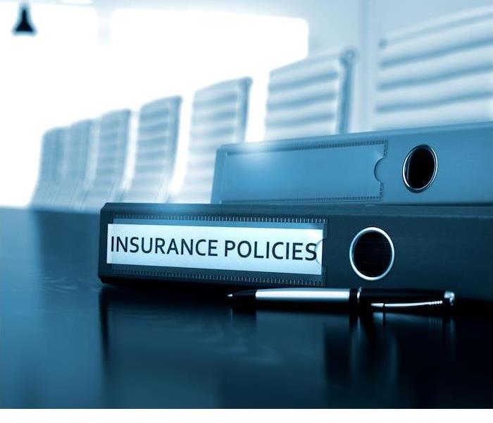insurance policies binders and pen sitting on black table in large conference room