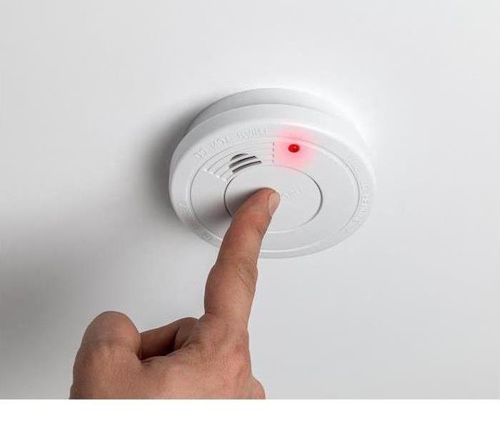 white fire alarm being tested by a person