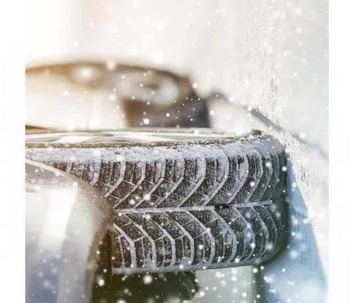 Close-up image of a car and tire moving through snow